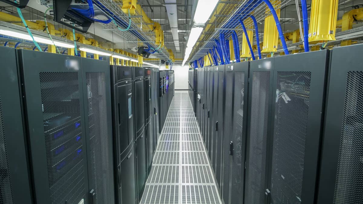 Rader med serverrack i en midtgang i et datasenter