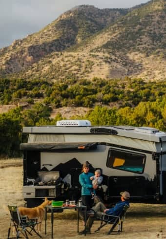 Familie som slapper av ved siden av campingbilen sin i fjellene